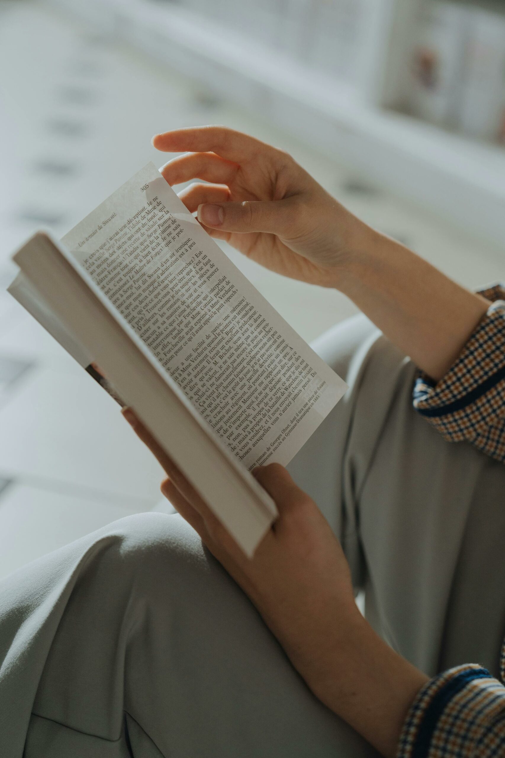 Close-up shot of hands holding an open book indoors with a soft focus background.